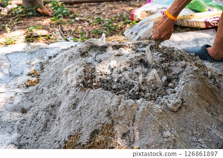 Manual concrete mixing with sand, cement and water, using shovel and trowel on outdoors Manual concrete mixing with sand, cement and water, using shovel and trowel on outdoors 126861897