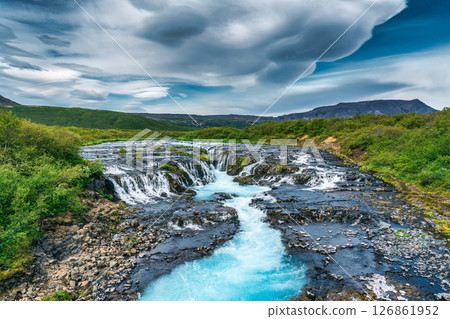 Vibrant bruarfoss waterfall flowing through rocky and wilderness in summer at Iceland 126861952