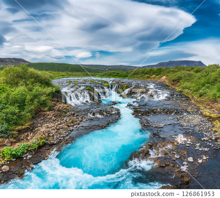 Vibrant bruarfoss waterfall flowing through rocky and wilderness in summer at Iceland 126861953