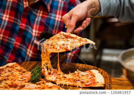 Delicious cheese meat pizza with stretchy melted cheese on wooden plate 126861957