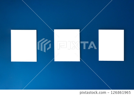 Three empty square canvas frames arranged on deep blue wall Three empty square canvas frames arranged on deep blue wall 126861965
