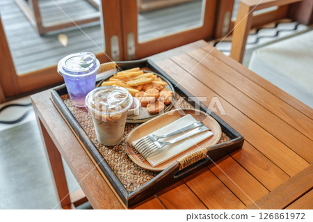 Tray contain of french fries, chicken nuggets, iced latte, butterfly pea drink served 126861972