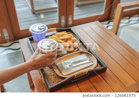 Woman reaching out to Iced latte with french fries, chicken nuggets, butterfly pea drink Woman reaching out to Iced latte with french fries, chicken nuggets, butterfly pea drink 126861973