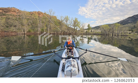 rowing scenery from a calm lake at foothills of Rocky Mountains with a senior rower 126862053