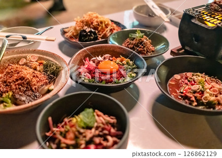 Isaan fusion food cuisine with various rare meat with herb, spicy salad on the table in restaurant Isaan fusion food cuisine with various rare meat with herb, spicy salad on the table in restaurant 126862129