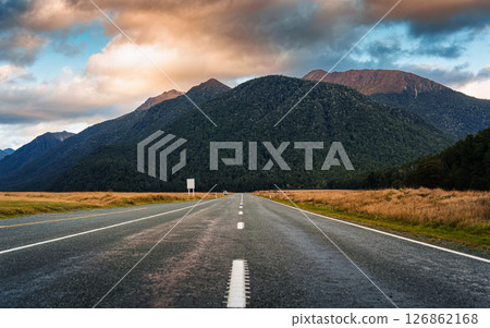 Straight Milford Road heading to mountain among meadow in the evening at New Zealand 126862168