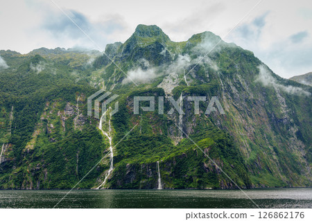 Milford Sound with waterfall flowing from limestone mountain with foggy in rainforest at New Zealand Milford Sound with waterfall flowing from limestone mountain with foggy in rainforest at New Zealand 126862176