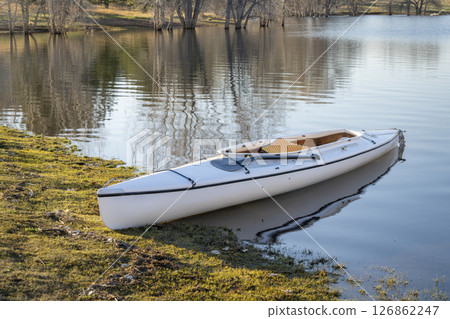 decked expedition canoe with a wooden paddle on a shore of Horsetooth Reservoir in northern Colorado in early spring scenery decked expedition canoe with a wooden paddle on a shore of Horsetooth Reservoir in northern Colorado in early spring scenery 126862247