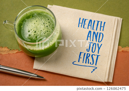 Health and joy first - positive affrmation, text on a napkin with glass of green juice 126862475