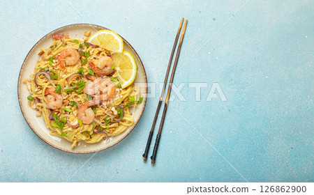 Pad thai noodles with shrimps and chopsticks on light blue background, traditional dish of Thailand, copy space 126862900