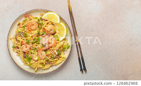 Pad thai noodles with shrimps and chopsticks on beige background, traditional dish of Thailand, space for text 126862908