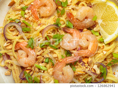 Pad thai noodles with shrimps, peanuts, green onions and lemon slice close up 126862941
