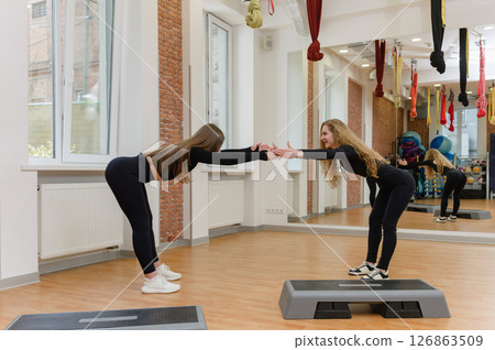 Two young women stretching in fitness studio mirror room. Two young women stretching in fitness studio mirror room. 126863509