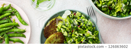 Enjoy zucchini and broccoli pancakes paired with a fresh mixed salad featuring cucumbers, young peas, and radishes Enjoy zucchini and broccoli pancakes paired with a fresh mixed salad featuring cucumbers, young peas, and radishes 126863602