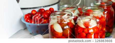 Canning ripe tomatoes and fresh tomato juice, preserving their natural taste for the winter months in airtight jars, kitchen table with prepared jars of tomatoes 126863608