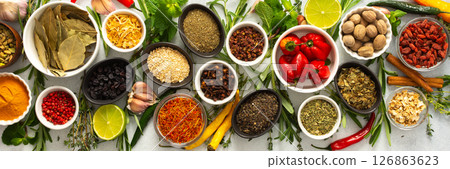 Assorted cooking spices and herbs arranged on a gray surface, featuring natural tones that add depth and aroma to any meal, banner 126863623