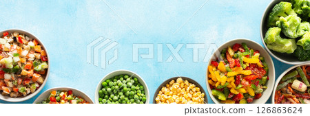 A variety of fresh vegetables frozen for winter, arranged on plates against a cool blue background, showcasing vibrant, seasonal produce ready for future meals, banner 126863624