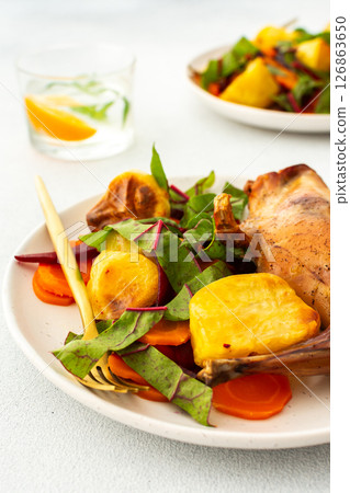 Enjoy a delicious, hearty meal with baked rabbit, roasted potatoes, and carrot salad, combining savory flavors and wholesome ingredients for a nutritious and satisfying dinner 126863650