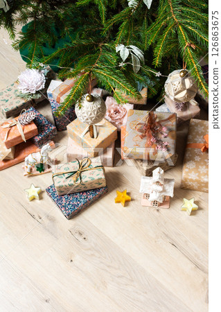 A cozy Christmas scene with elegant natural-toned gift boxes placed under a Christmas tree, lit with festive lights, evoking peace and seasonal joy A cozy Christmas scene with elegant natural-toned gift boxes placed under a Christmas tree, lit with festive lights, evoking peace and seasonal joy 126863675