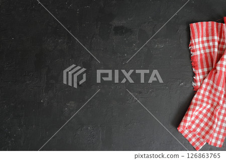 Black concrete background with red checkered textile. Copy space, flat lay. 126863765