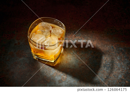 Whiskey in a square glass with ice on a vintage background. 126864175