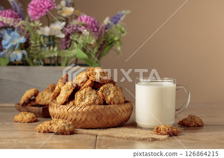 Oatmeal cookies and milk sit on a kitchen table. 126864215