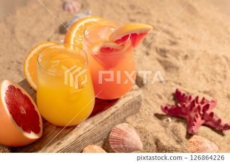 Grapefruit and orange cocktails with fresh fruits on a beach. Grapefruit and orange cocktails with fresh fruits on a beach. 126864226