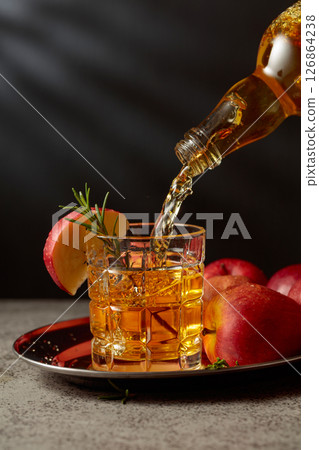 Apple cider is poured from a bottle into a glass. Apple cider is poured from a bottle into a glass. 126864238