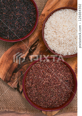 set of red and black and white rice, in a bowl, on a wooden surface, rustic style, top view 126864302