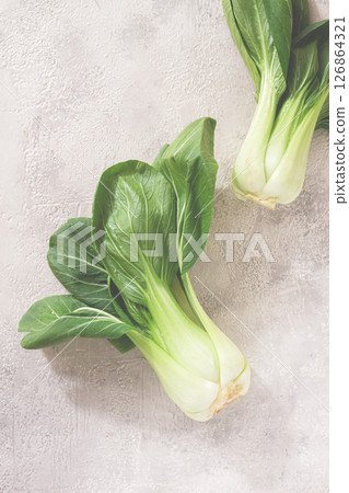 Fresh bok choy, laid out on a light gray surface, top view, natural light, 126864321