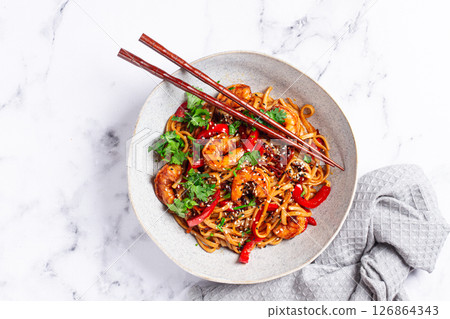 udon noodles, shrimp with vegetables and fresh herbs, in a bowl with chopsticks, light background, homemade, no people, 126864343