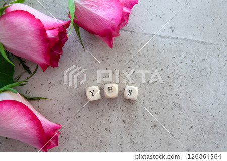 Positive answer - yes. Exclamation word on the stone table background with rose flowers. 126864564