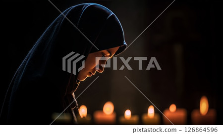 Nun in a tranquil church prays in candlelight, reflecting deep faith and devotion in a serene atmosphere 126864596