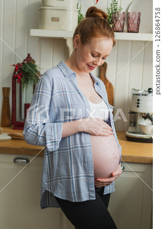 Pregnancy motherhood people expectation future. Pregnant woman with big belly smiling in kitchen at home. Girl hugging her tummy enjoying pregnancy. Maternity tenderness parenthood new life concept Pregnancy motherhood people expectation future. Pregnant woman with big belly smiling in kitchen at home. Girl hugging her tummy enjoying pregnancy. Maternity tenderness parenthood new life concept 126864758