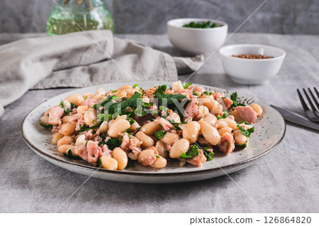 Appetizing salad with tuna, white beans and greens on a plate on the table 126864820