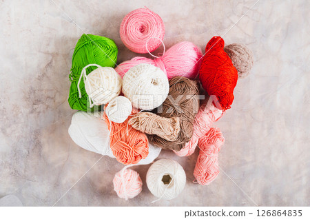 Many colored skeins of yarn in a pile on a table top view 126864835