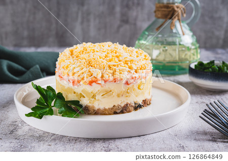 Traditional layered salad with canned fish on a plate on the table 126864849