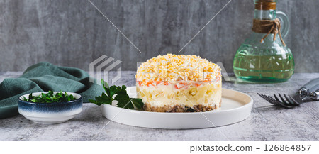 Traditional layered salad with canned fish on a plate on the table web banner 126864857