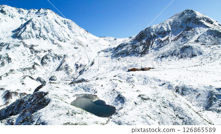 Aerial view of the snowy landscape of Murododaira, Mt. Tateyama, and the thin ice of Mikurigaike Pond and the Tateyama mountain range 126865589