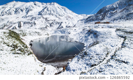 Aerial view of the snowy landscape of Murododaira, Mt. Tateyama, and the thin ice of Mikurigaike Pond and the Tateyama mountain range 126865592