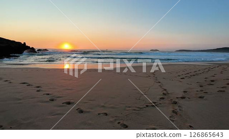 The Breathtaking Sunset Over the Tranquil Beach with gentle Waves crashing upon the shore The Breathtaking Sunset Over the Tranquil Beach with gentle Waves crashing upon the shore 126865643