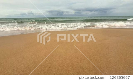 The Calm Beach Waves at Dusk Gently Crash Against the Shoreline, Surrounded by Golden Sand The Calm Beach Waves at Dusk Gently Crash Against the Shoreline, Surrounded by Golden Sand 126865667