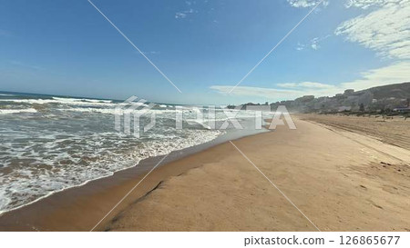 A Serene and Beautiful Beach View Featuring Gentle Waves Rolling Under a Bright Sunny Sky A Serene and Beautiful Beach View Featuring Gentle Waves Rolling Under a Bright Sunny Sky 126865677