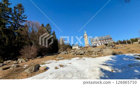 A breathtaking and scenic mountain view adorned with snow and a towering structure nearby A breathtaking and scenic mountain view adorned with snow and a towering structure nearby 126865710