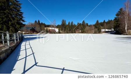 A Stunningly Beautiful Frozen Lake Under a Clear Blue Sky in a Serene Winter Landscape A Stunningly Beautiful Frozen Lake Under a Clear Blue Sky in a Serene Winter Landscape 126865740