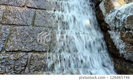 A Serene Waterfall Cascading Gently Over a Beautiful Stone Wall Surrounded by Nature 126865746