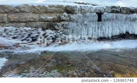 A Frozen Waterfall with an Icy River Flowing Gently Through a Beautiful Wilderness 126865748