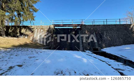 A Beautiful Snowy Landscape Featuring a Bridge and a Unique Stone Structure Present A Beautiful Snowy Landscape Featuring a Bridge and a Unique Stone Structure Present 126865750