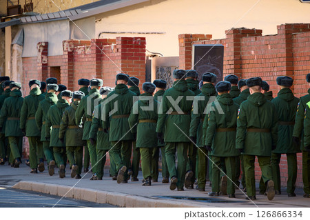 a column of cadets of military forces walk along the fence and gates with the symbols of the armed forces 126866334