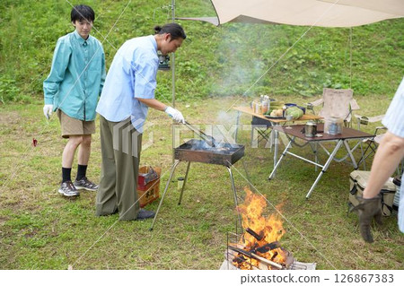 Camping friends preparing for a barbecue Camping friends preparing for a barbecue 126867383